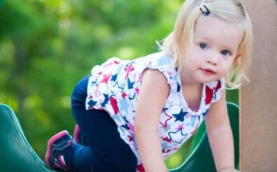 Parenting toddlers isn't for the faint of heart. Blonde toddler girl on play equipment.
