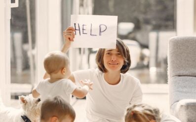 mom holding up help sign with her kids around her