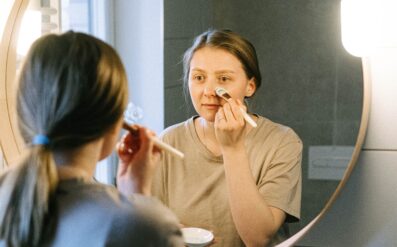 mother doing skincare in the mirror alone