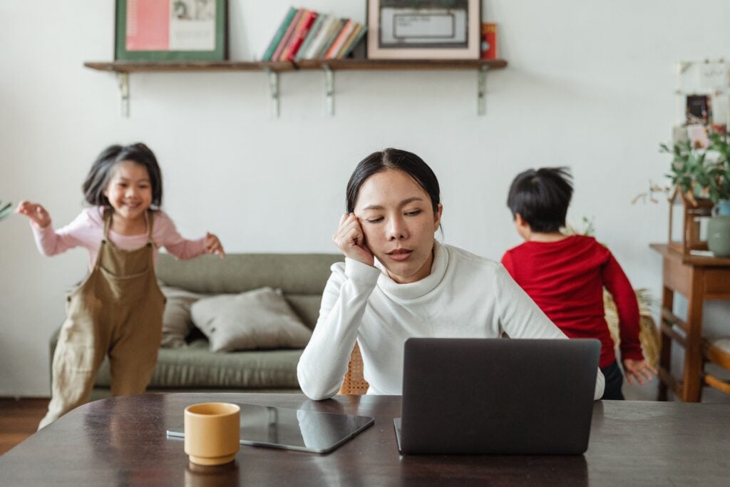 stressed out mom at the computer and kids running around in the background