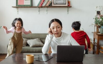 stressed out mom at the computer and kids running around in the background
